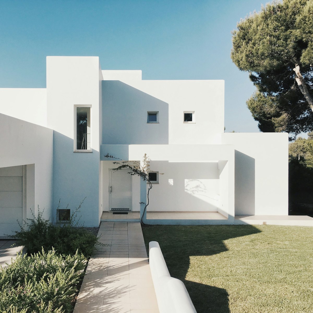 White modern custom residence with a landscaped walk